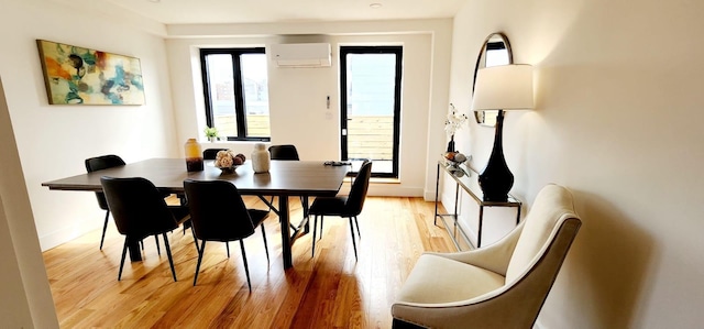 dining room featuring light wood-type flooring, baseboards, and an AC wall unit