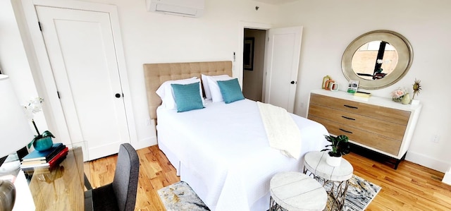 bedroom featuring baseboards, a wall mounted air conditioner, and light wood-style floors