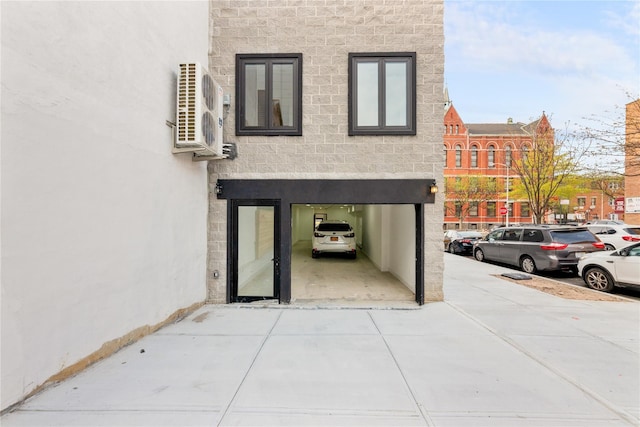 exterior space with ac unit, driveway, and stone siding
