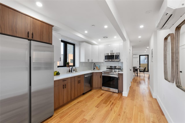 kitchen with a sink, light countertops, stainless steel appliances, white cabinetry, and light wood-type flooring