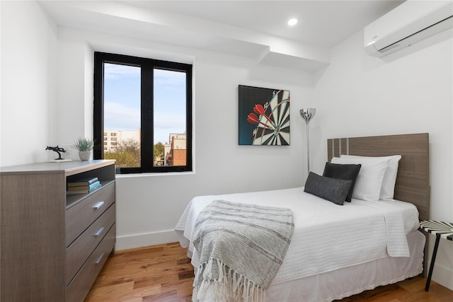 bedroom with recessed lighting, baseboards, a wall unit AC, and light wood-style flooring