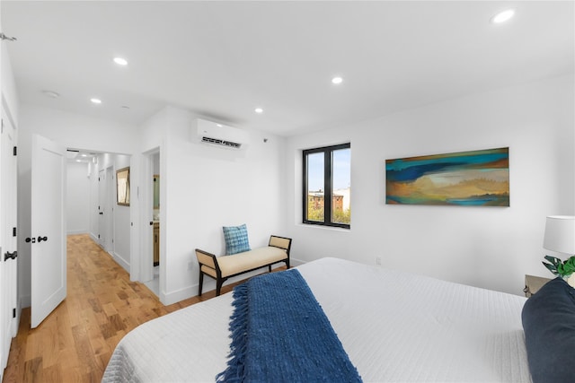 bedroom featuring recessed lighting, baseboards, a wall unit AC, and light wood-type flooring