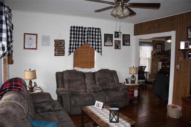 living room with dark hardwood / wood-style floors, ceiling fan, and wooden walls