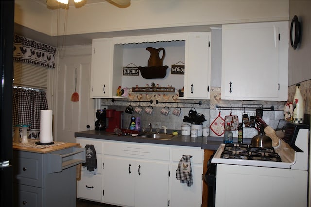 kitchen with decorative backsplash, white cabinetry, white gas stove, and sink