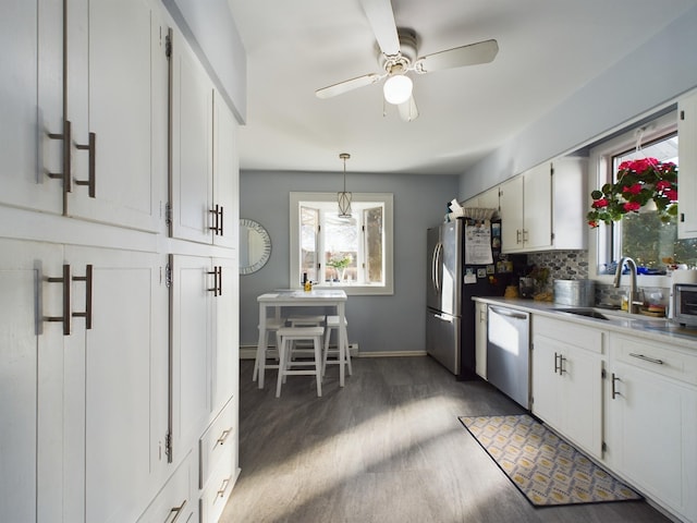 kitchen featuring white cabinets, sink, decorative backsplash, decorative light fixtures, and stainless steel appliances