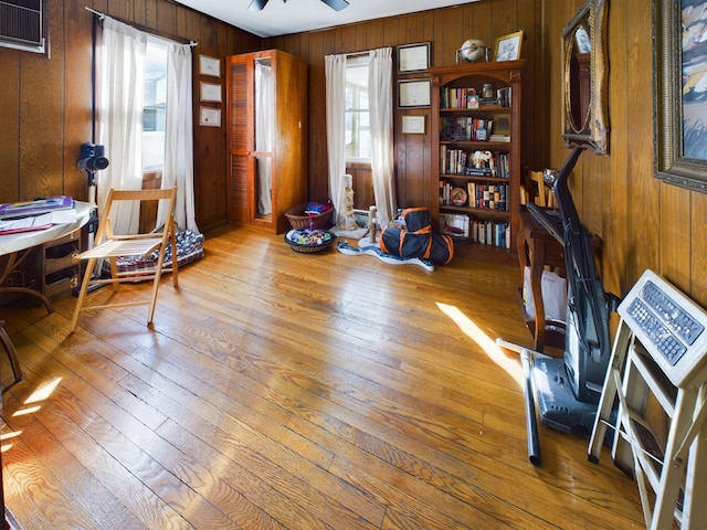 interior space with wooden walls, ceiling fan, light hardwood / wood-style floors, and a wealth of natural light