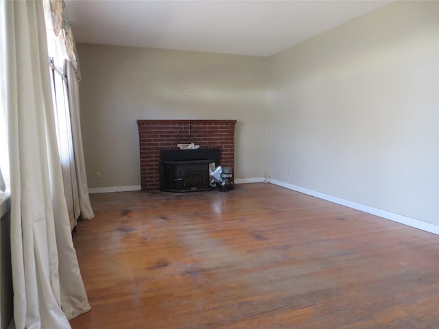 unfurnished living room featuring wood-type flooring and a wood stove