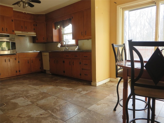 kitchen featuring ceiling fan, sink, stovetop, oven, and white dishwasher