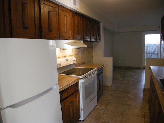 kitchen featuring tile patterned flooring, white appliances, extractor fan, and tasteful backsplash