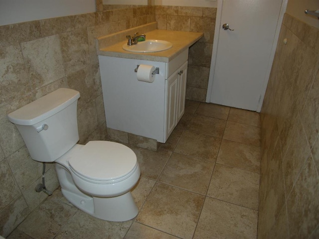 bathroom featuring vanity, tile walls, and toilet