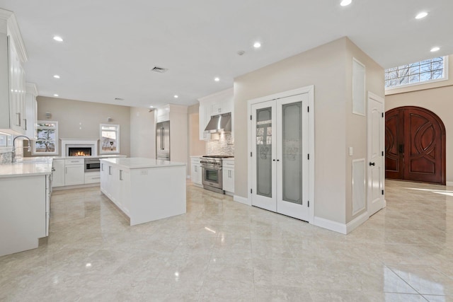 kitchen featuring white cabinetry, decorative backsplash, a kitchen island, high quality appliances, and sink