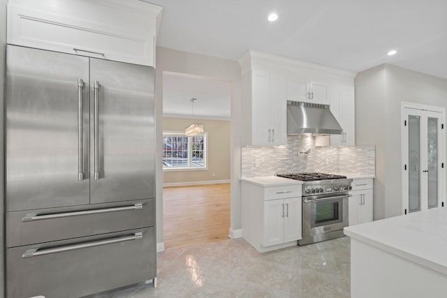 kitchen with ventilation hood, premium appliances, white cabinets, and light stone countertops