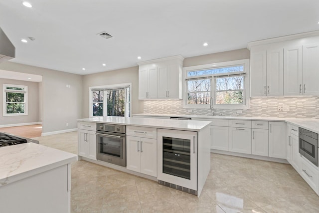 kitchen featuring sink, appliances with stainless steel finishes, beverage cooler, and white cabinetry