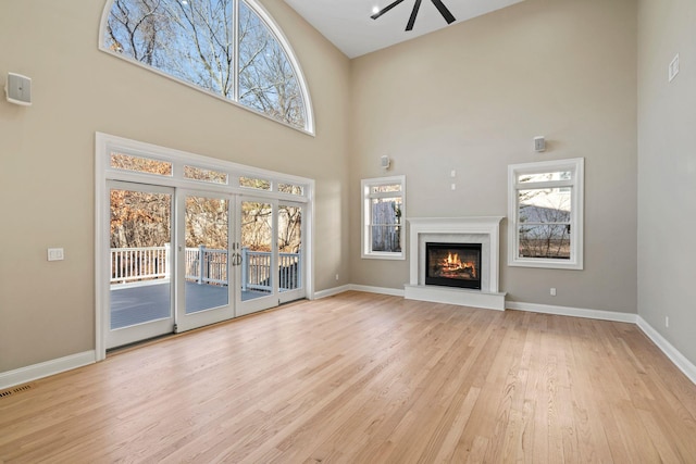 unfurnished living room featuring a high ceiling, french doors, and light wood-type flooring