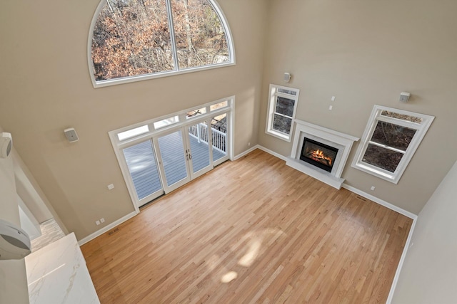 living room with french doors, a towering ceiling, and light hardwood / wood-style flooring