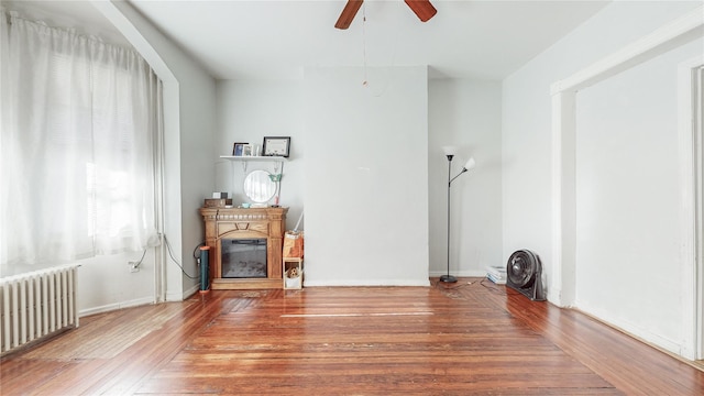 unfurnished living room with ceiling fan, wood-type flooring, and radiator