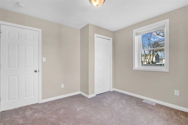 unfurnished bedroom with light colored carpet and a closet