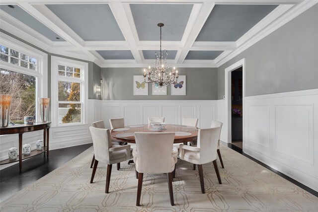 dining room with a notable chandelier, beamed ceiling, light wood-style flooring, and a wainscoted wall