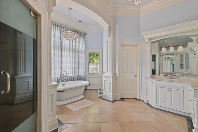 bathroom with a notable chandelier, a freestanding bath, vanity, and ornamental molding