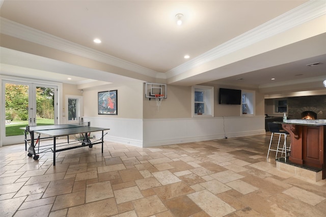 playroom featuring stone tile floors, visible vents, wainscoting, and ornamental molding