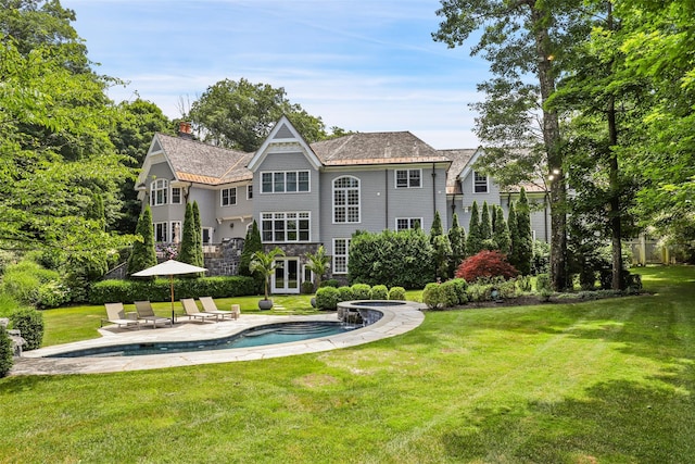 back of property with a patio area, an outdoor pool, a chimney, and a yard