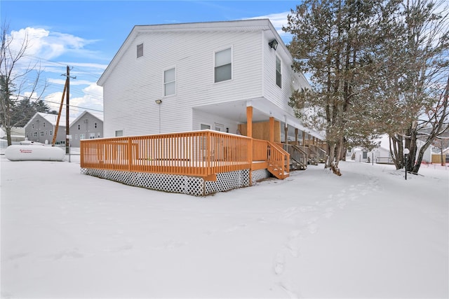 snow covered back of property featuring a wooden deck