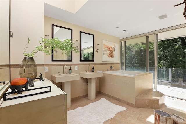 bathroom featuring a relaxing tiled tub, tile patterned floors, and floor to ceiling windows