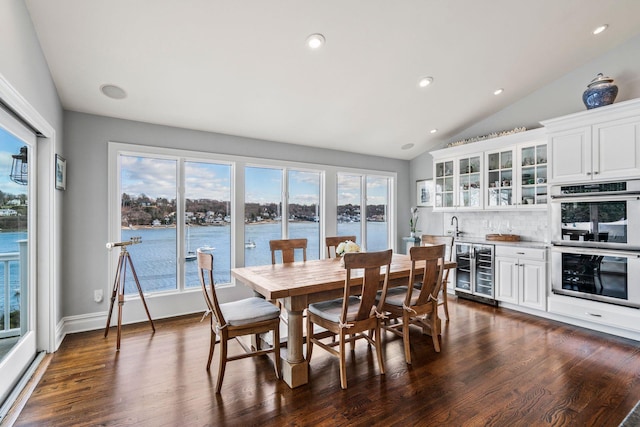 dining area featuring wine cooler, a wealth of natural light, a water view, and vaulted ceiling