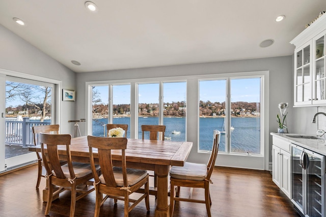 dining space with lofted ceiling, sink, a water view, dark hardwood / wood-style floors, and beverage cooler