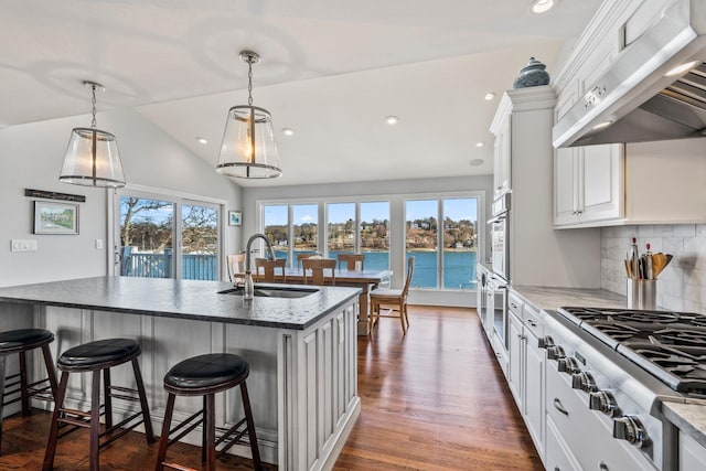 kitchen featuring extractor fan, sink, white cabinets, stainless steel gas cooktop, and a water view