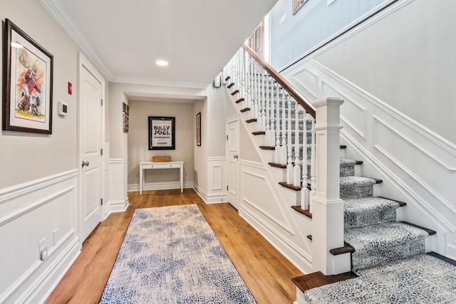 staircase featuring ornamental molding and wood-type flooring