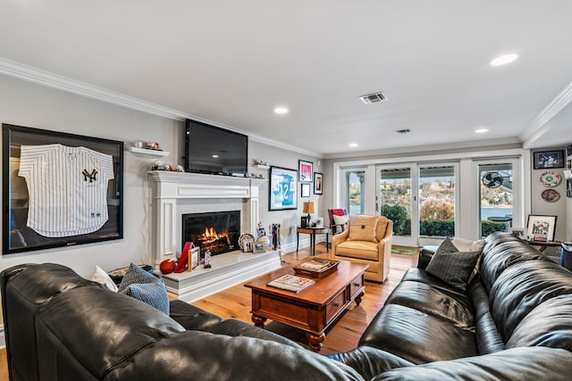 living room featuring hardwood / wood-style flooring, ornamental molding, a fireplace, and french doors