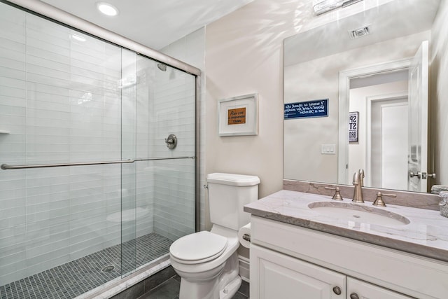 bathroom featuring vanity, a shower with door, and toilet