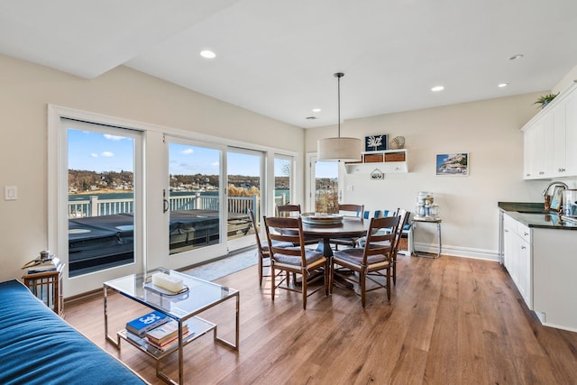 dining area featuring a water view, sink, and light wood-type flooring