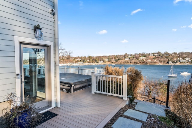 wooden terrace featuring a water view and a covered hot tub