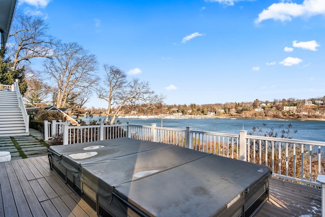 wooden terrace with a covered hot tub and a water view