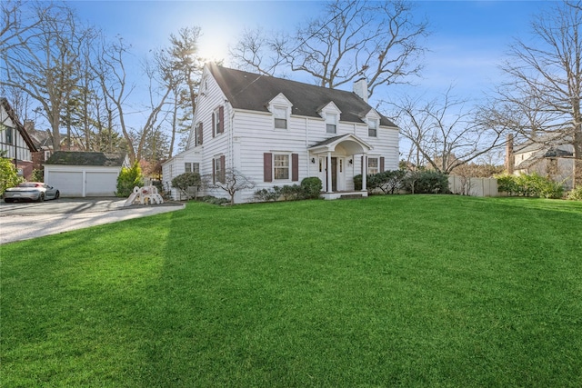 view of front facade featuring a garage, a front yard, and an outbuilding