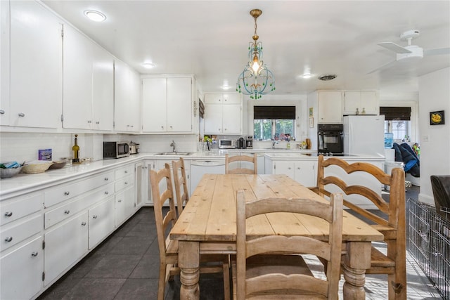 kitchen with white cabinetry, dark tile patterned floors, hanging light fixtures, and white appliances