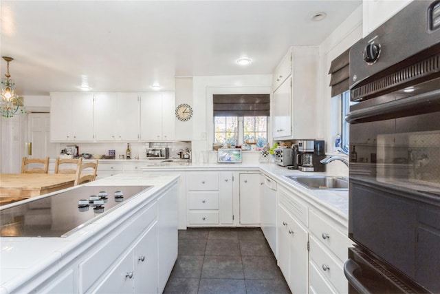 kitchen featuring sink, pendant lighting, white cabinets, and black appliances