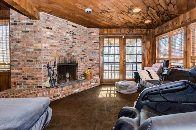 living room with wood ceiling, wooden walls, carpet, a fireplace, and french doors