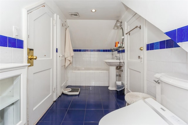 bathroom featuring tiled bath, tile walls, tile patterned floors, and toilet