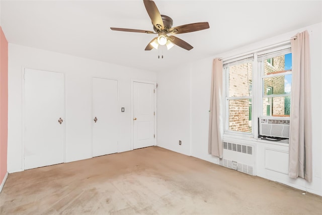 unfurnished bedroom with ceiling fan, light colored carpet, radiator, and multiple closets