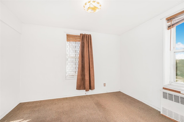 empty room with radiator, a wealth of natural light, and carpet flooring