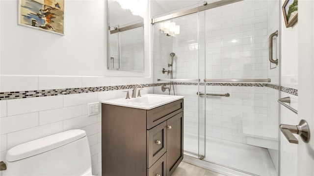 bathroom with a shower with shower door, tile walls, toilet, and vanity