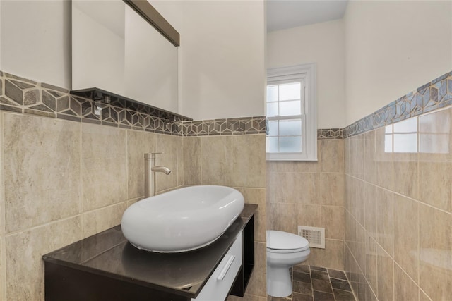 bathroom featuring tile walls, toilet, and vanity