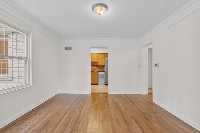 empty room featuring light wood-type flooring and crown molding