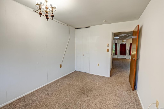 carpeted spare room with a notable chandelier