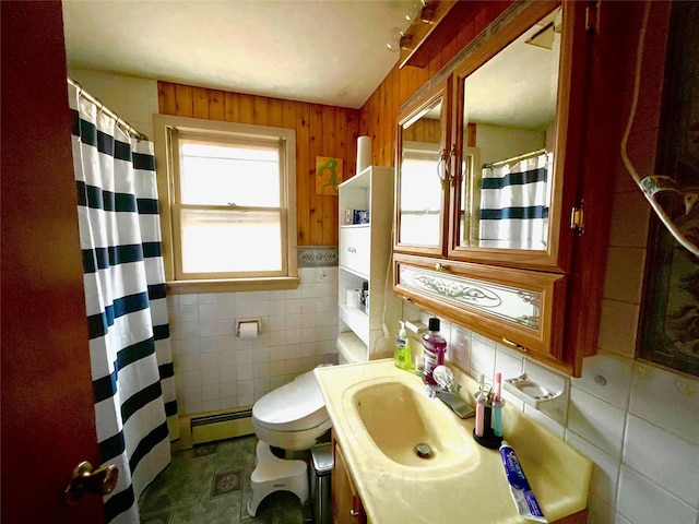 bathroom featuring a healthy amount of sunlight, toilet, baseboard heating, and tile walls