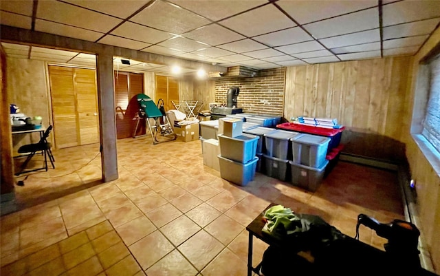 basement with a paneled ceiling and wood walls