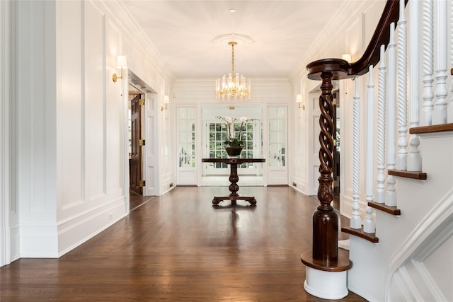 entrance foyer featuring a notable chandelier, dark wood-type flooring, and ornamental molding